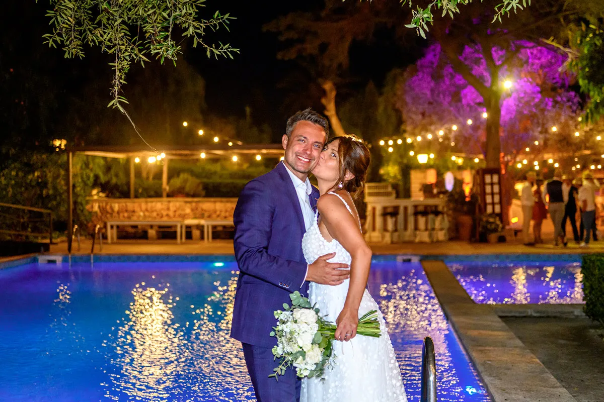 Novios de noche junto a la piscina iluminada