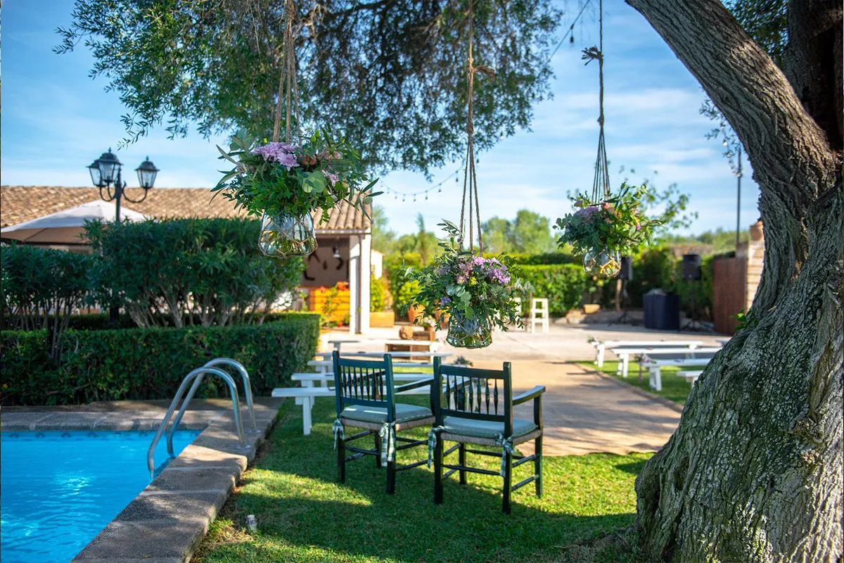 Rincón del jardín junto a la piscina, con mesas y sillas